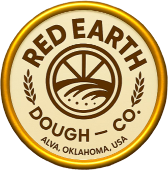 Red Earth Dough Co. circular company logo featuring stylized wheat fields and grain graphics representing agricultural roots, dough production, and food manufacturing. The logo includes the company name “Red Earth Dough Co.” and the location “Alva, Oklahoma, USA,” emphasizing American-made frozen pizza crust production, wheat-based food innovation, and commercial pizza manufacturing